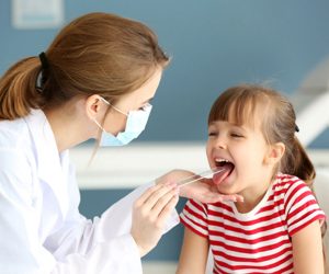 enfermeira usando máscara coloca abaixador de língua em uma menina para ver se ela está com dor de garganta