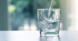água sendo colocada em um copo de vidro transparente