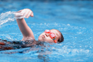 Criança nadando em uma piscina com óculos de natação