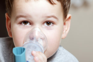 rosto de menino usando um inalador devido a uma crise de asma